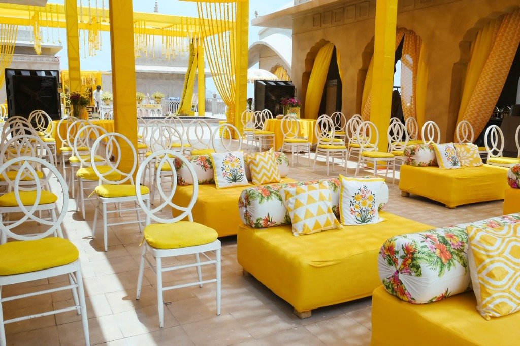 Vibrant yellow haldi ceremony setup with matching chairs and lounge decor