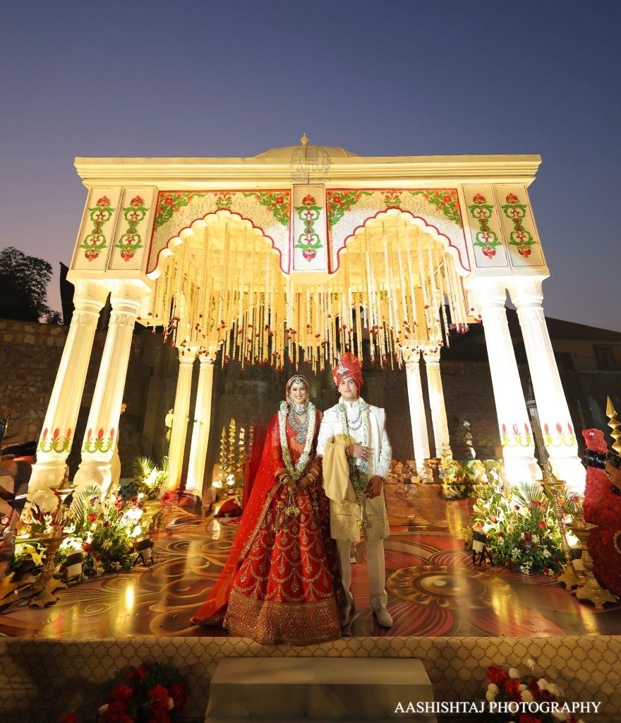 Elegant Indian wedding mandap with illuminated white arches and couple